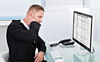 person with hand on face staring at computer screen containing spreadsheet