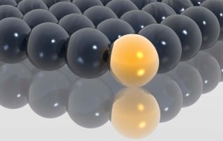 many black balls and one yellow ball all touching on flat surface