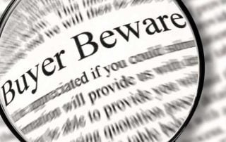 magnifying glass hovering above newspaper with words "Buyer Beware" magnified